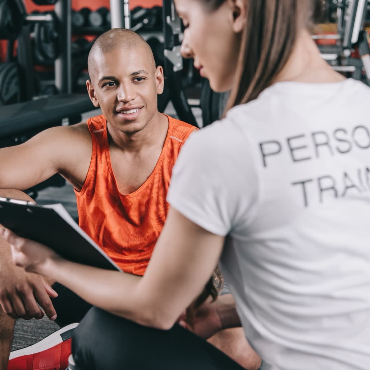 Personal Trainer im Gespräch mit einem Kunden im Fitnessstudio